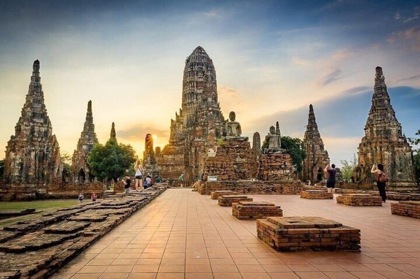 Ancient temple ruins with multiple structures, a paved walkway, and visitors. 4