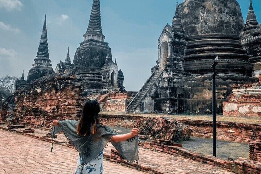 A woman standing in front of ancient temple ruins with multiple tiered spires. 5