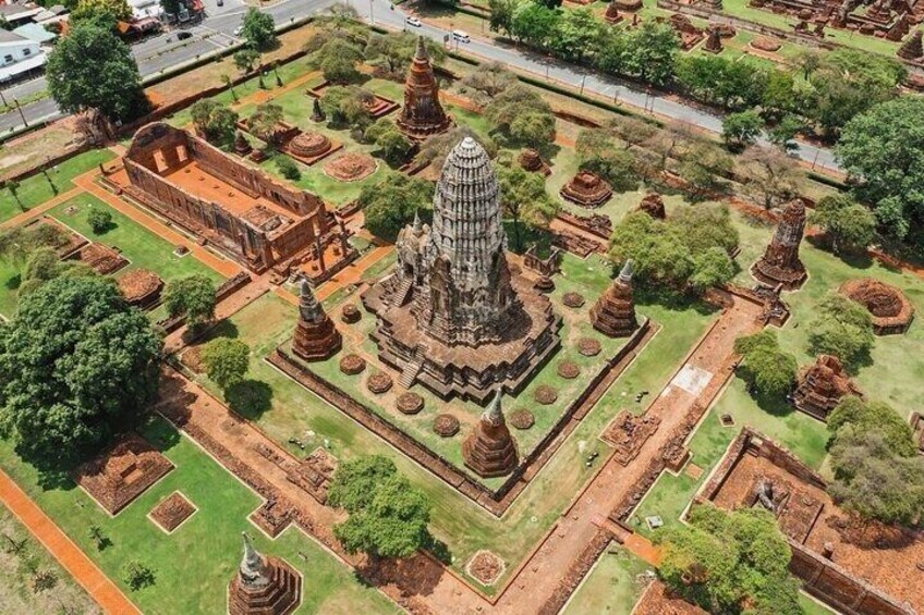 An ancient temple complex with multiple structures, including a central stupa and smaller stupas, surrounded by well-maintained gardens and pathways. 2