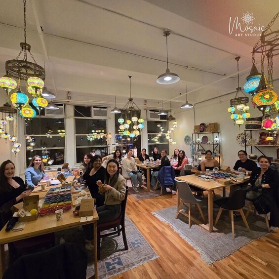 A group of people in a well-lit room with hanging decorative lights and wooden furniture. 2