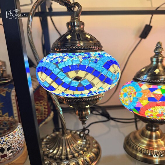 A mosaic lamp with a blue and yellow pattern, a brass base, and a decorative handle. 5