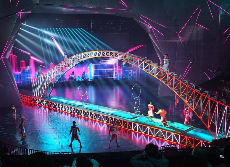 A stage with a geometric design, performers, and a cityscape backdrop. 4