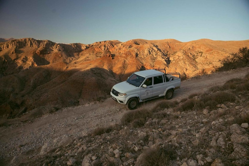 A white SUV on a rocky trail with a mountainous landscape in the background. 2