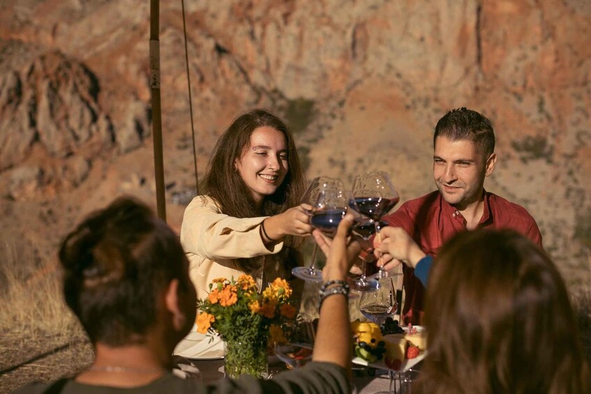 A group of people toasting with wine glasses at a table with a floral centerpiece. 4