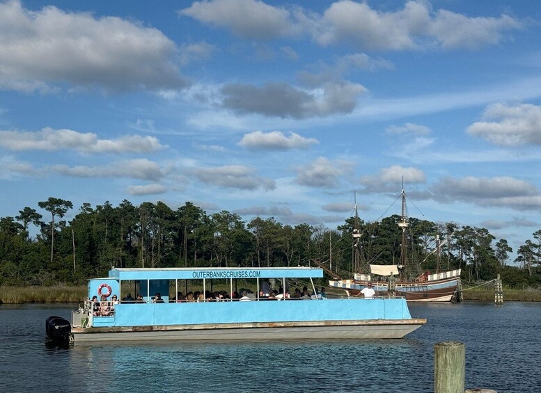 A blue boat with people on board, docked near a forested shore. 3