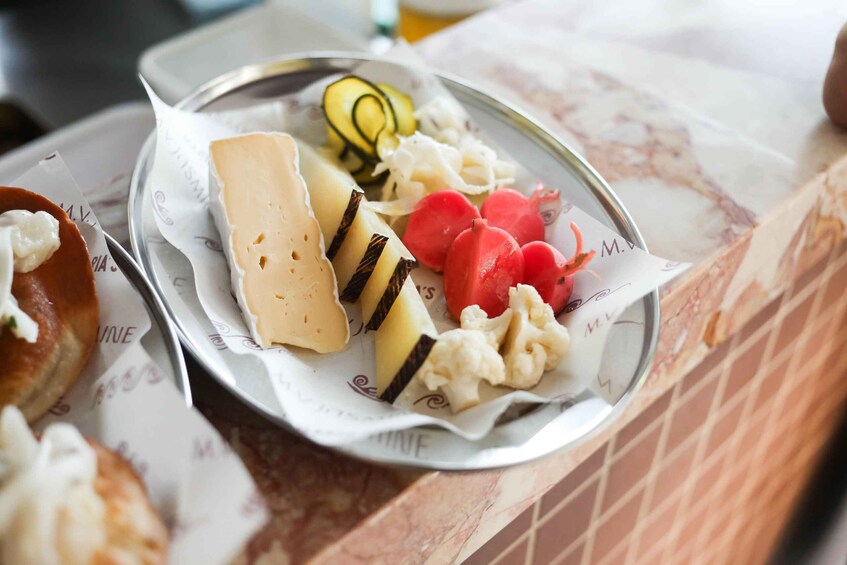 A plate with cheese, sliced vegetables, and a pomegranate. 5