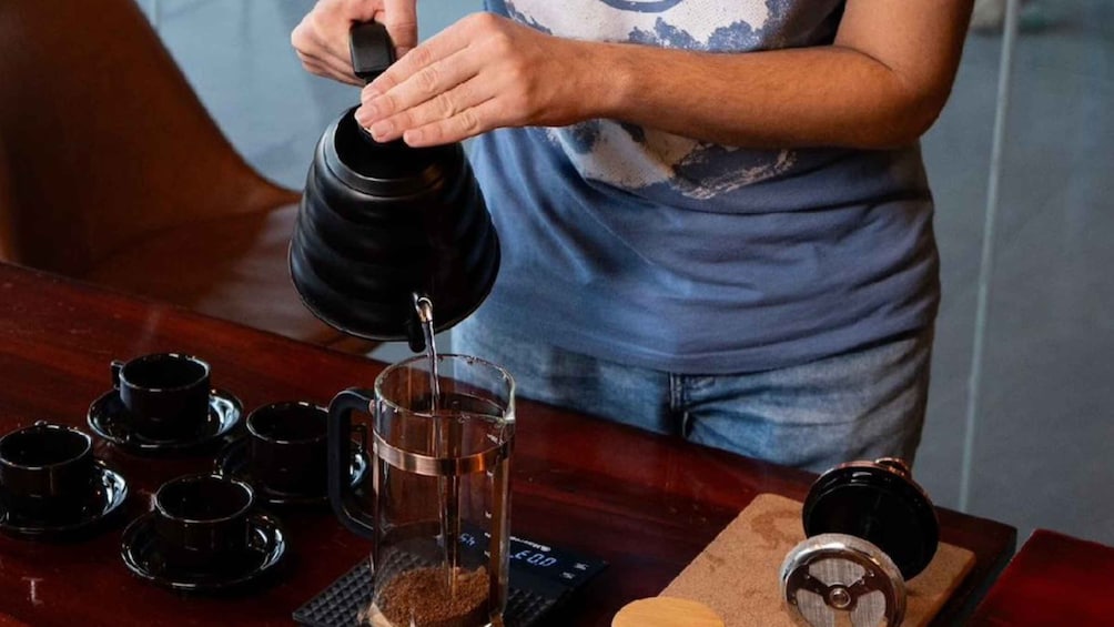 A person pouring liquid from a kettle into a glass. 5