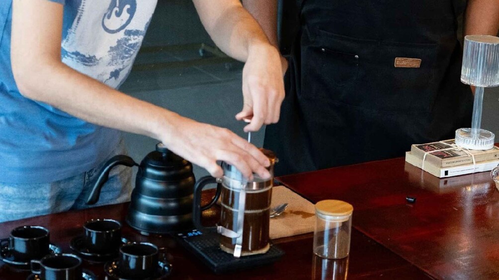 A person preparing coffee with a coffee press on a wooden board. 5