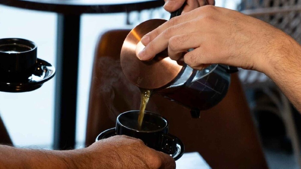 A person pouring coffee into a cup. 1