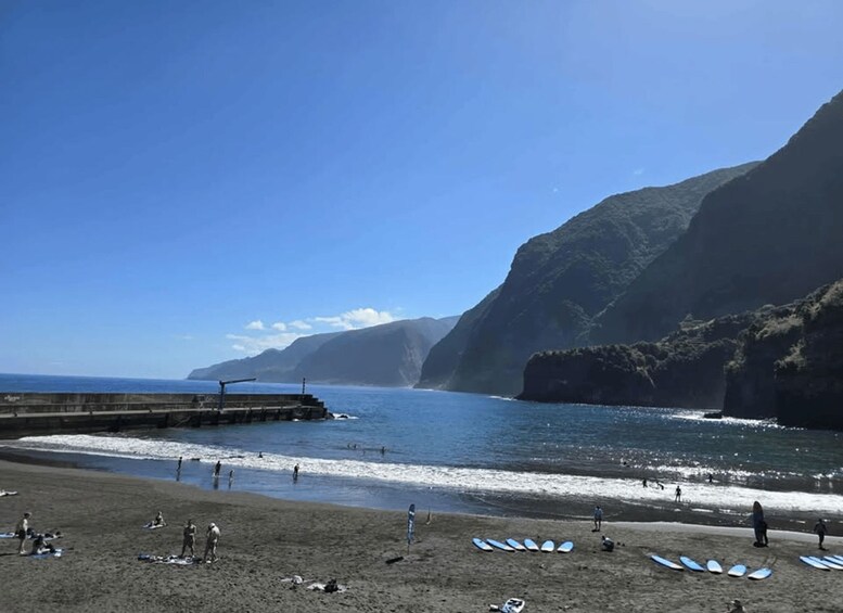A beach with people, waves, and surfboards. 5