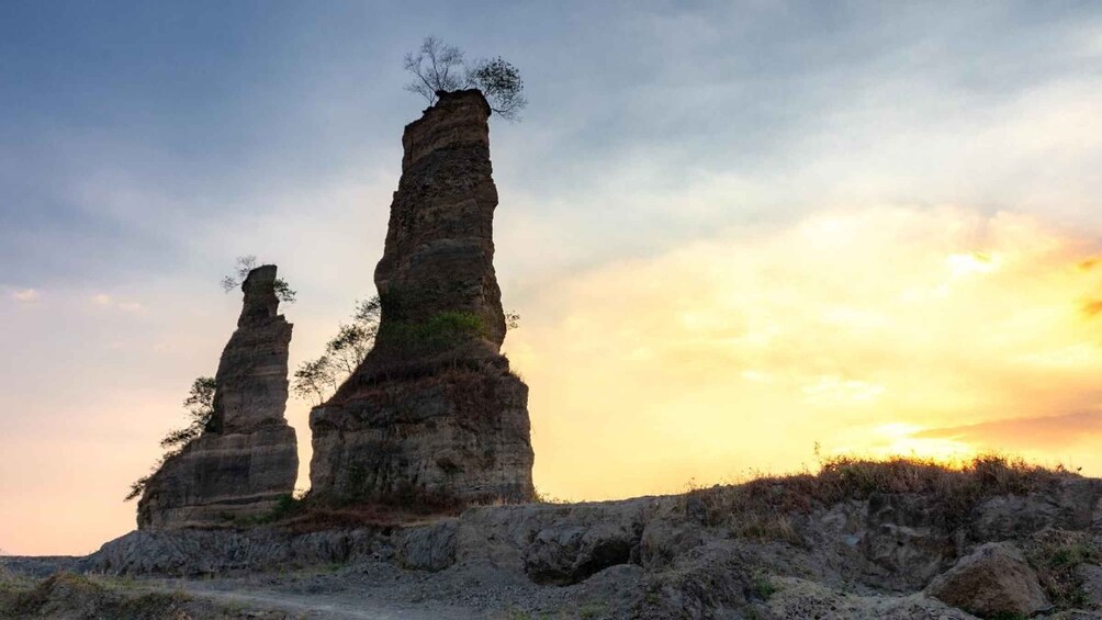 Two prominent rock formations with sparse vegetation, set against a sunset sky. 5