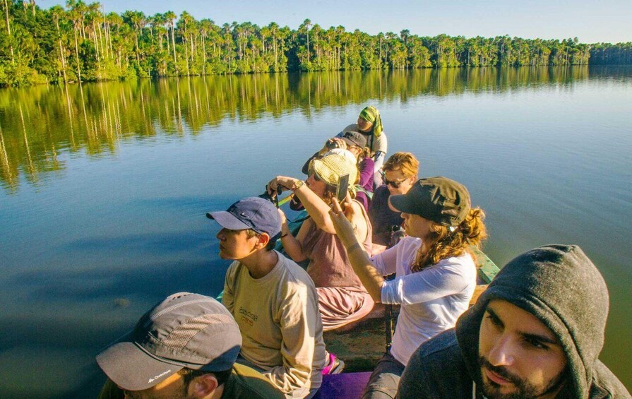A group of people on a boat in a calm lake surrounded by dense forest. 5