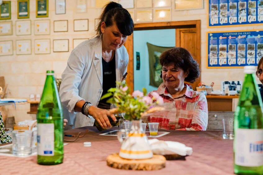 Two people at a table with a green bottle, a vase with flowers, and a menu board in the background. 5
