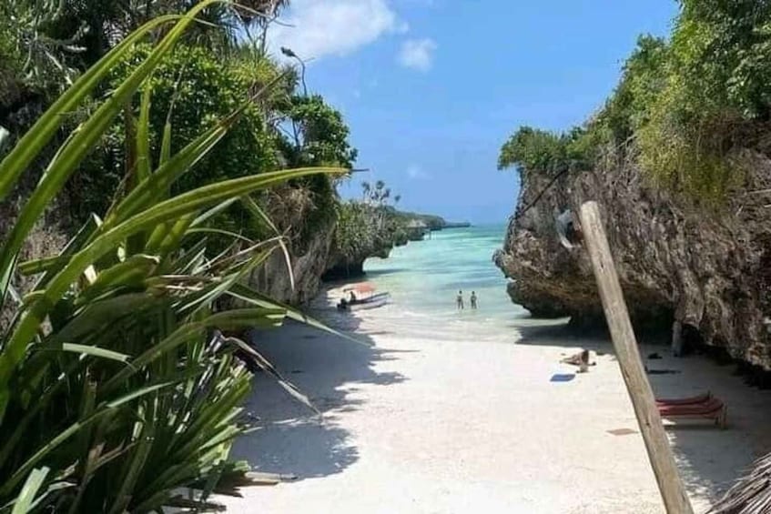A beach with clear turquoise water, a sandy shore, and a rocky cliff. 4