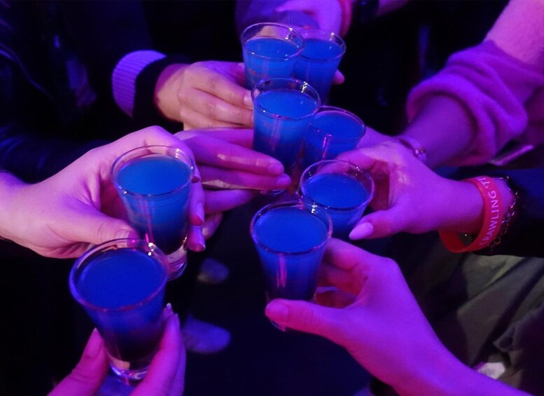 A group of people holding glasses filled with a blue liquid, likely at a social event. 2
