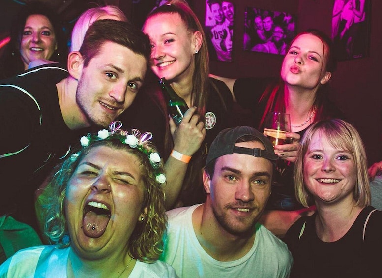 A group of people at a social event with dim lighting and a purple hue. 1