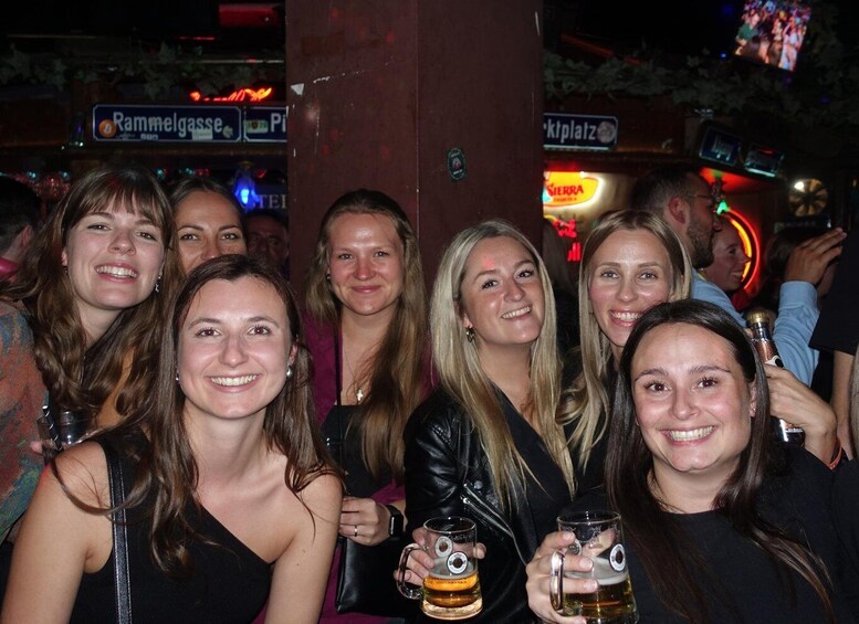 A group of people at a bar with neon signs and a dartboard in the background. 5