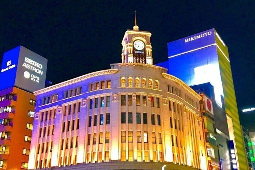 A brightly lit building with a clock tower, surrounded by other illuminated buildings. 5