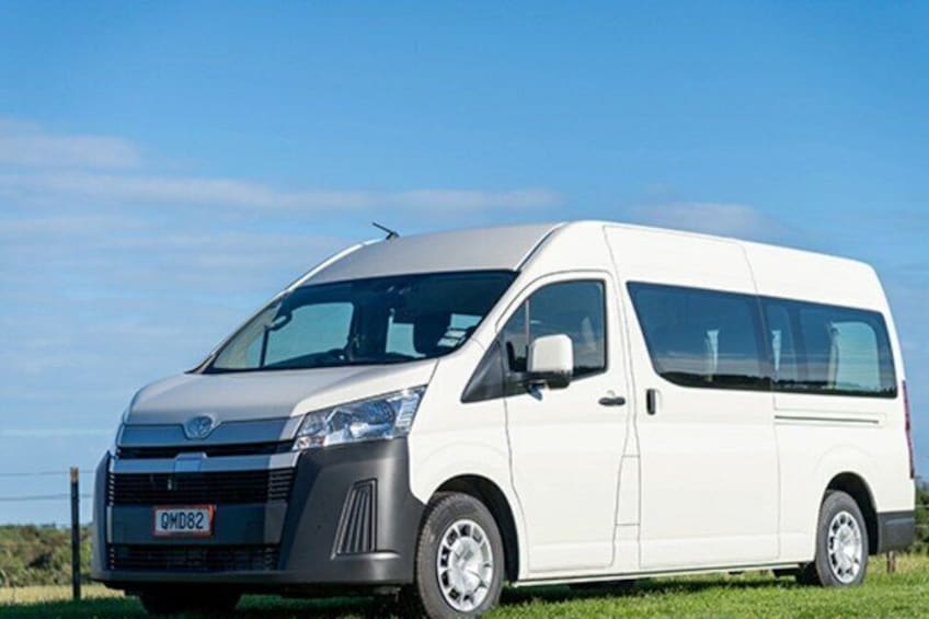 A white van parked on a grassy field with a clear blue sky in the background. 2