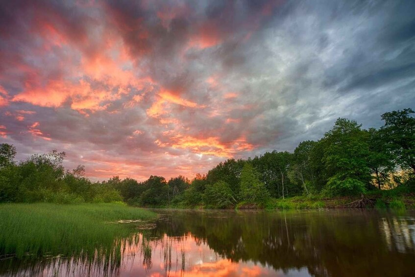 A sunset over a calm lake with trees reflecting the sky. 2