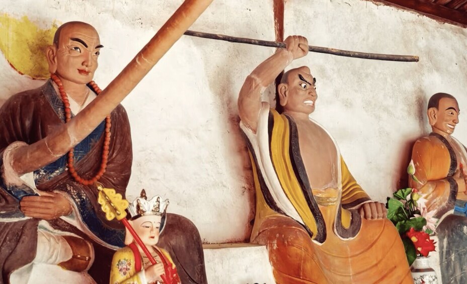 A statue of a figure holding a staff, another figure with a crown, and a third figure in a yellow robe. 2