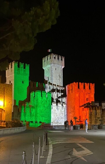 A castle illuminated with green, white, and red lights. 5