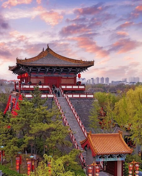 A traditional Chinese building with a red roof and white walls, surrounded by trees and a cityscape in the background. 1