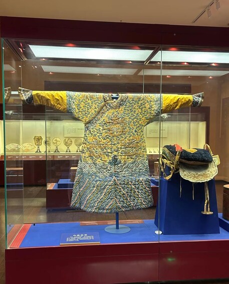 A museum display with a traditional garment and a fan. 4
