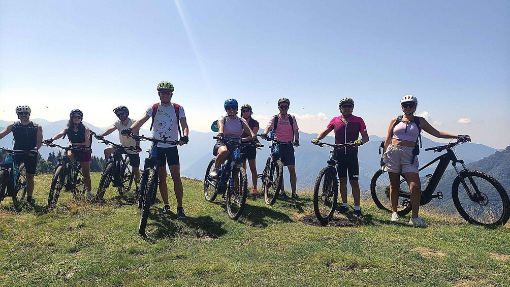A group of cyclists on a grassy hill with mountains in the background. 5