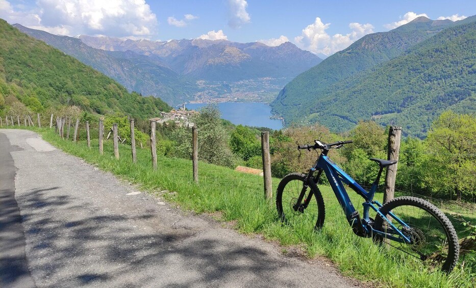 A mountain road with a blue mountain bike parked on the side. 2