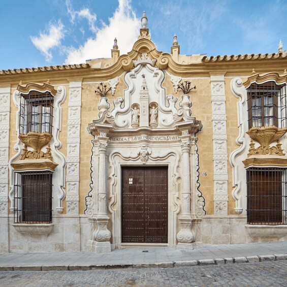 A historic building with ornate architecture, including a decorative entrance and two large windows with wrought iron grilles. 1