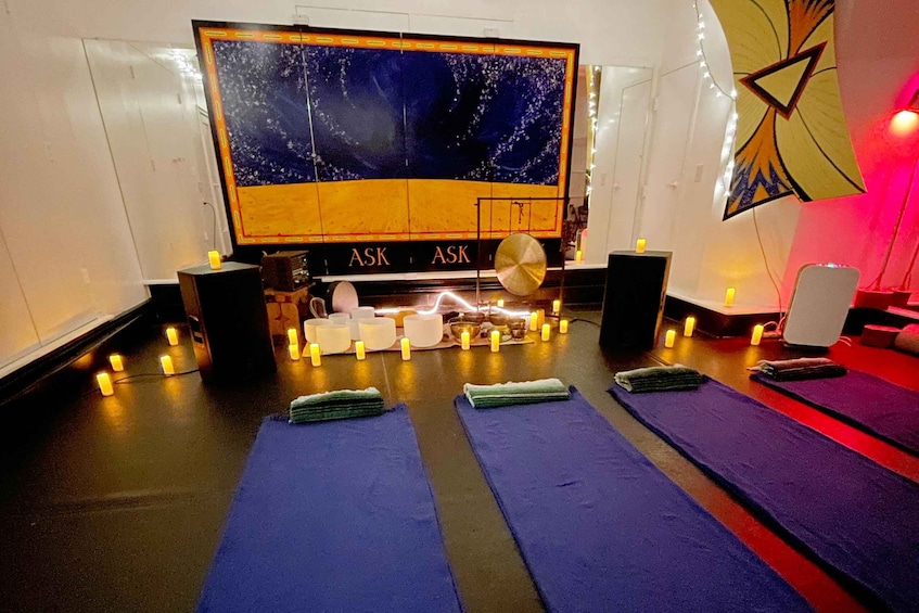 A room with a large screen displaying a night scene, a table with candles, and yoga mats. 5