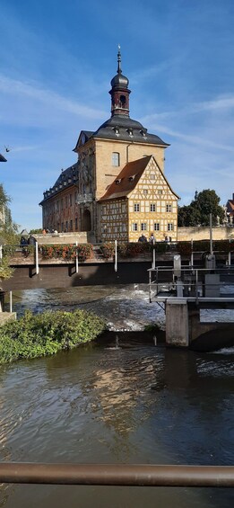 A historic building with a clock tower, a river in the foreground, and a clear blue sky. 4