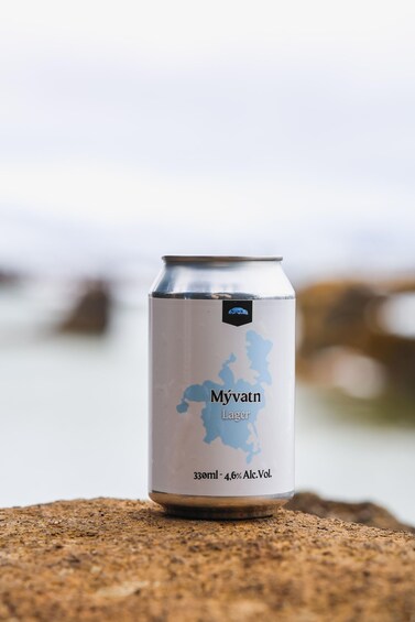 A can of Myvatn Lager beer with a map of Iceland on the label, placed on a rocky surface near a body of water. 3