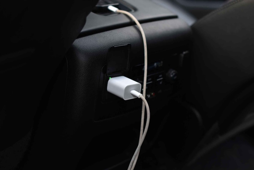 A car's dashboard with a charging cable plugged into a USB port. 5