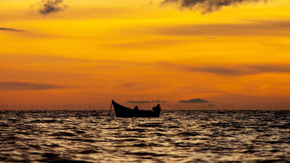 A sunset over the ocean with a boat carrying people. 3