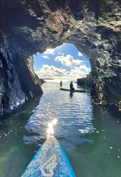 A kayak in a narrow waterway between rocky cliffs with a clear sky above. 1