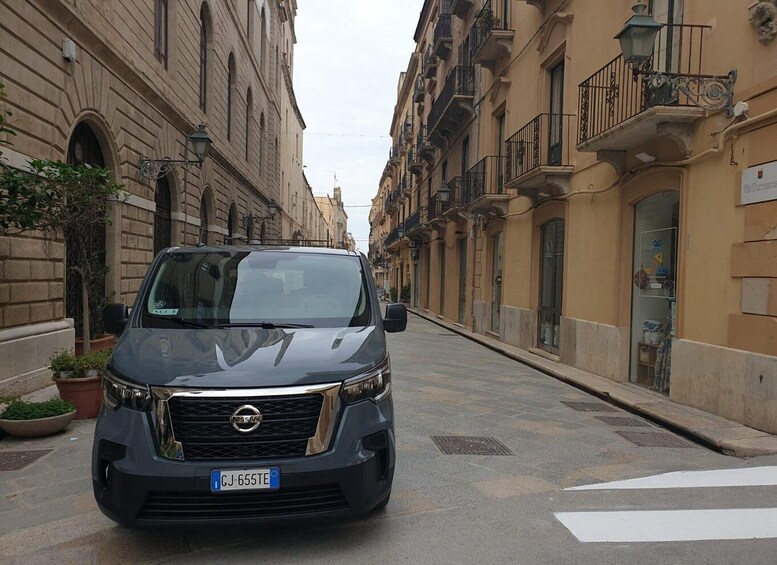 A dark-colored Nissan SUV parked on a street lined with historic buildings. 4