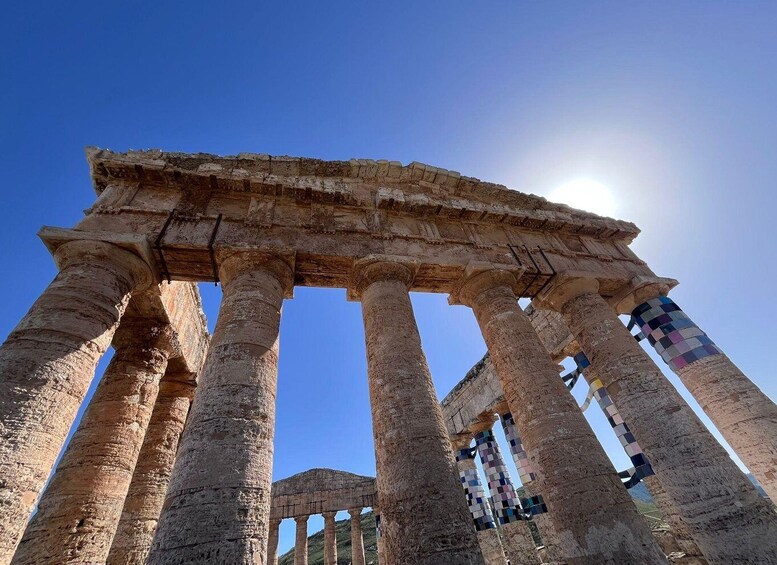 Ancient stone columns with a clear blue sky and sun in the background. 5