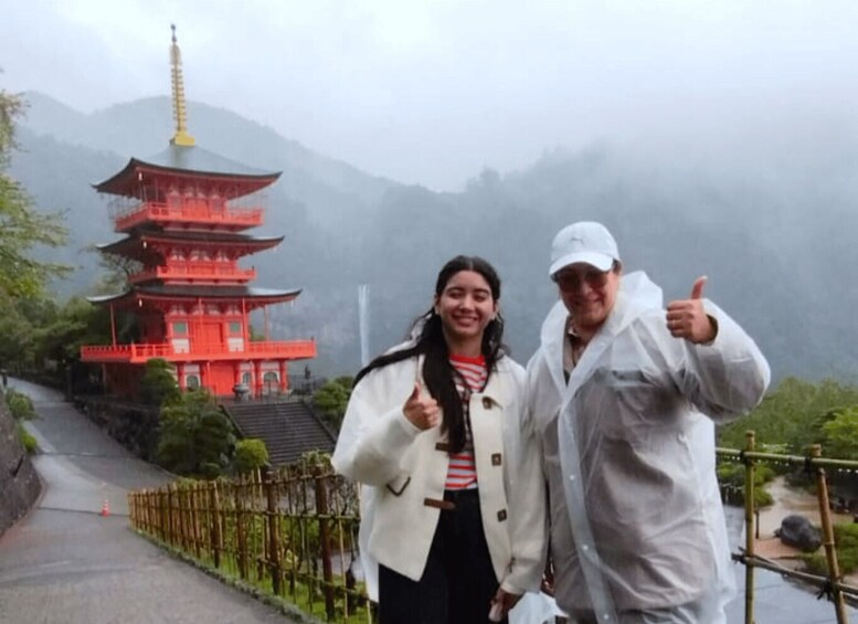 A red pagoda, a person giving a thumbs-up, and a person in a white raincoat. 1