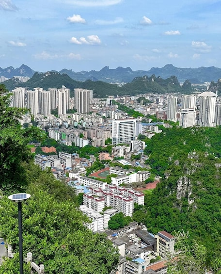 A cityscape with high-rise buildings, a dense urban area, and a mountainous backdrop. 3