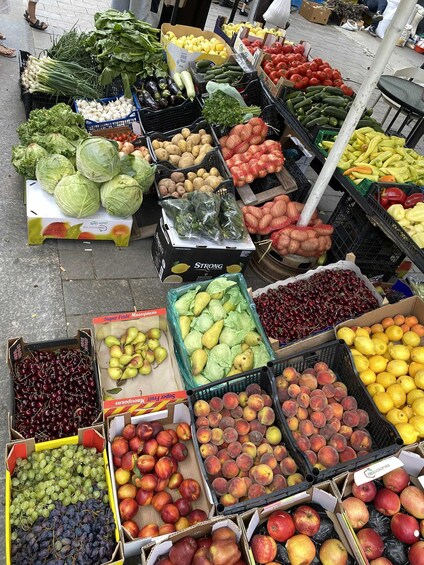 A variety of fresh produce including cabbages, potatoes, tomatoes, and fruits like apples and cherries at a market. 3