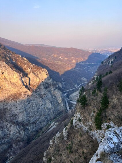 A mountainous landscape with a winding road, rocky terrain, and sparse vegetation. 4