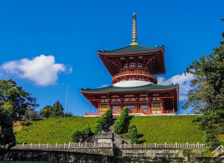A traditional Japanese pagoda with a multi-tiered roof, surrounded by lush greenery and a clear blue sky. 1
