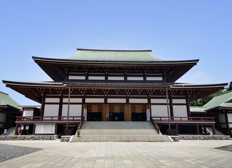 A traditional Japanese temple with a large wooden structure, a tiled roof, and a stone staircase leading up to the entrance. 4