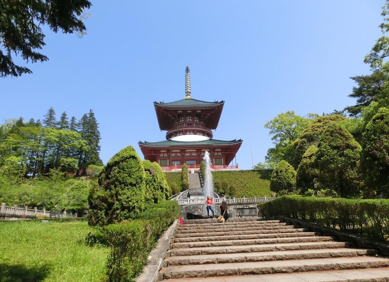 A traditional Japanese pagoda with a multi-tiered roof, surrounded by lush greenery and a stone staircase leading up to it. 3