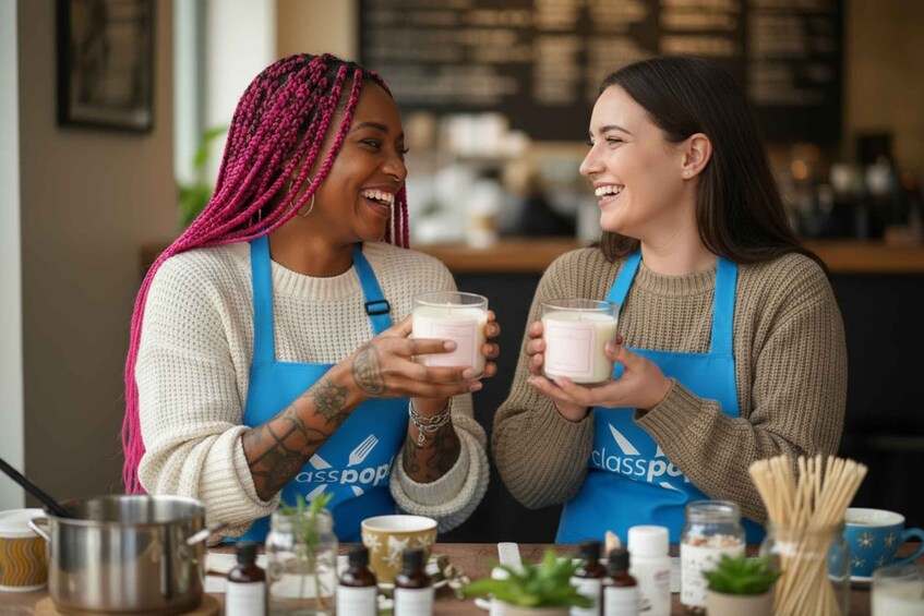Two people in aprons holding candles, with various items like a pot, jars, and a cup on the table. 1