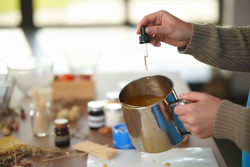 A person pouring a clear liquid from a dropper into a metal cup. 2
