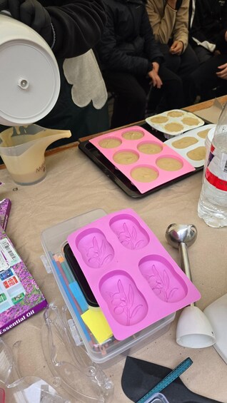 A baking activity with muffin tins, a pink silicone mold, and baking tools on a table. 3
