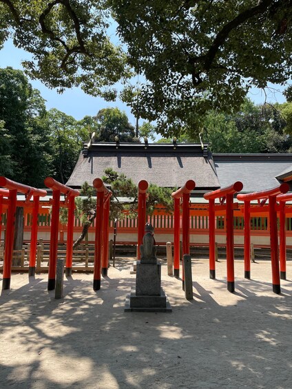 A traditional Japanese shrine with red torii gates, a stone lantern, and a thatched roof structure. 4